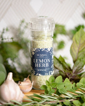 Load image into Gallery viewer, Summa Salts Lemon Herb Salt grinder surrounded by fresh herbs, lemon slices, and coarse sea salt, styled on a wooden board.

