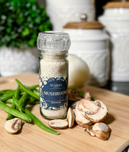 Glass grinder of Mushroom Salt showing coarse salt and mushroom flecks.